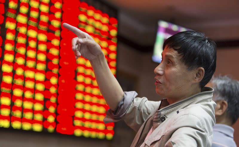An investor gestures as he speaks to other investors in front of an electronic board showing stock information at a brokerage house in Nanjing, Jiangsu province, China, June 4, 2015. REUTERS/China Daily