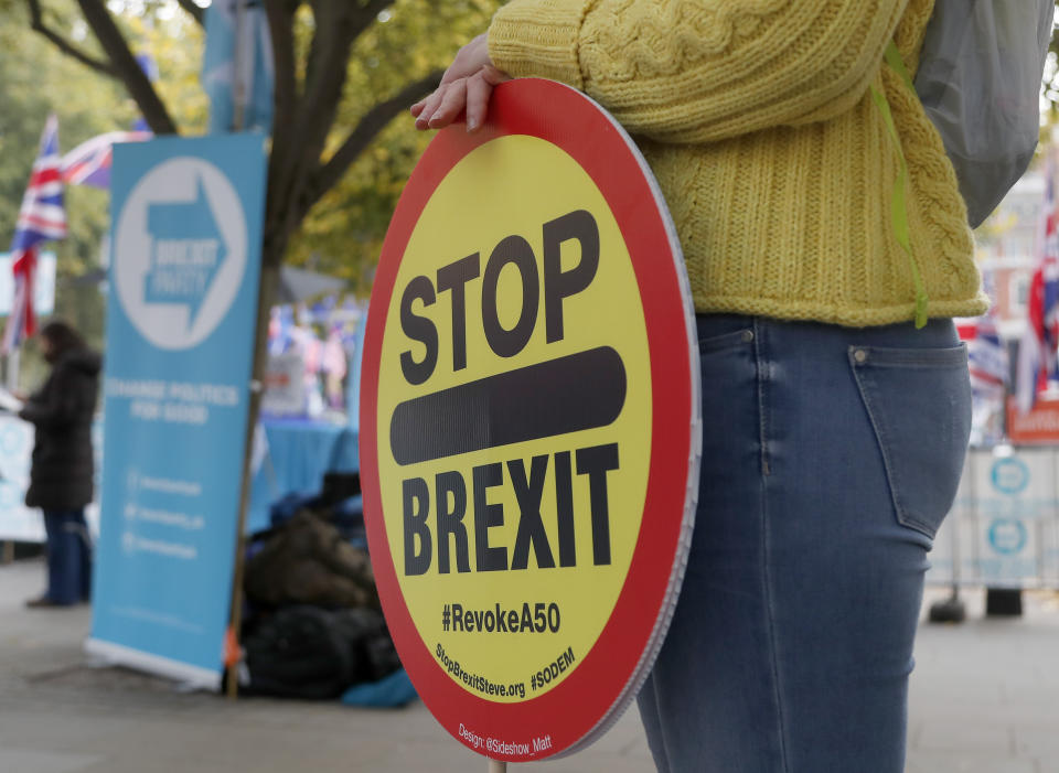 Anti Brexit protestors show their posters in front of parliament in London, Wednesday, Oct. 23, 2019. Britain's government is waiting for the EU's response to its request for an extension to the Brexit deadline. (AP Photo/Frank Augstein)