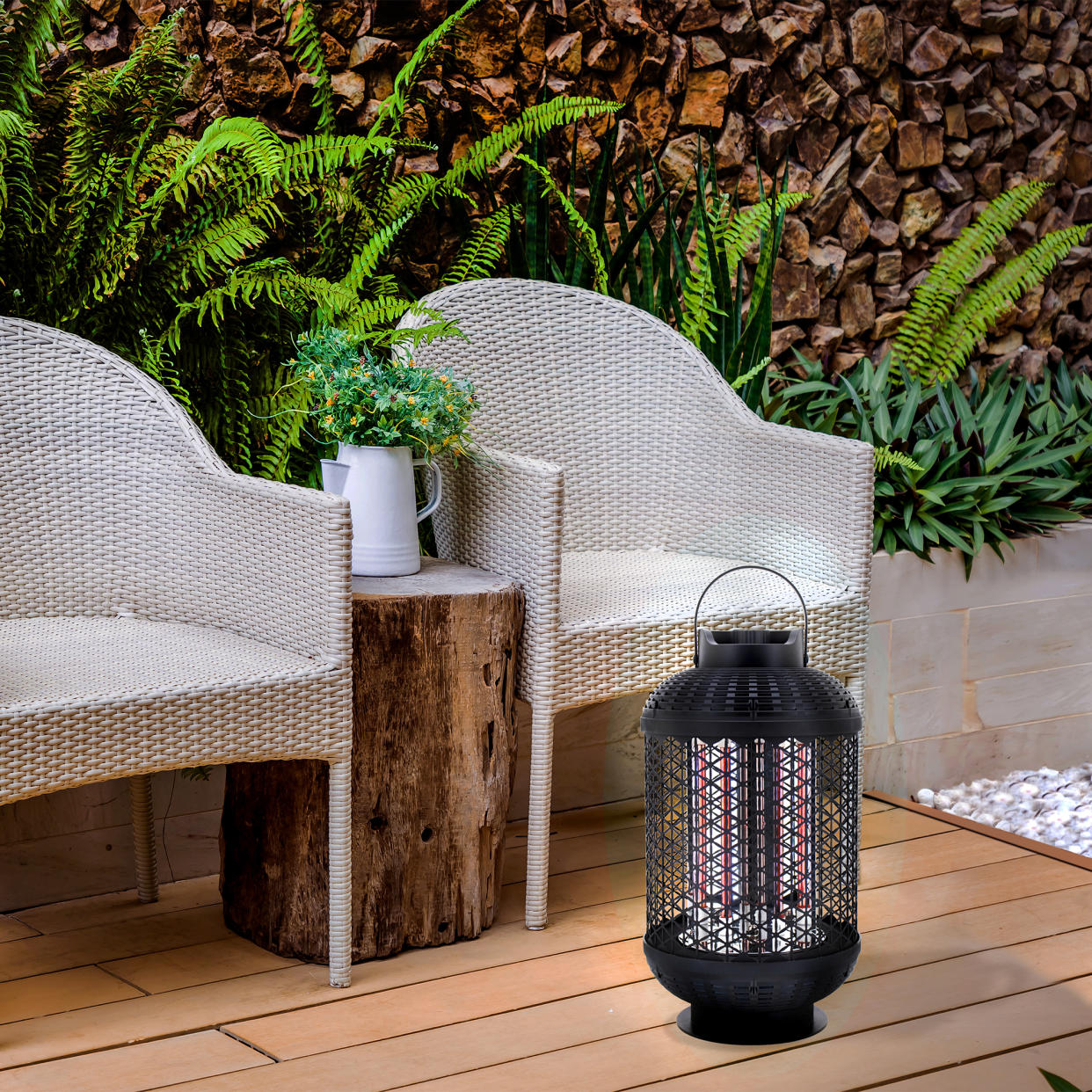  A small lantern electric patio heater on the flloor by two grey rattan outdoor chairs 