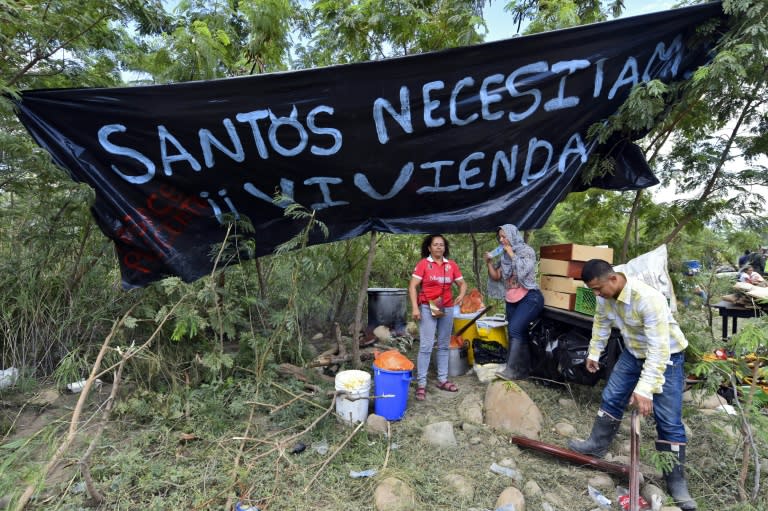 A Colombian family is seen next to a banner reading "Santos, we need housing" (referring to Colombian President Juan Manuel Santos) in Cucuta, Colombia after crossing the border from Venezuela on August 26, 2015
