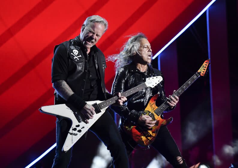 Two musicians play electric guitars onstage during a concert