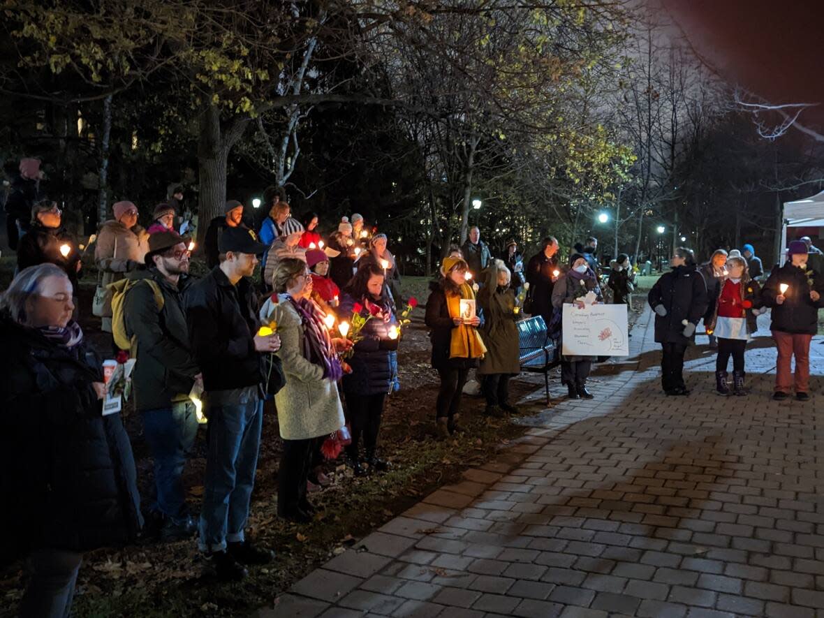 More than 50 people gathered at Philosopher's Walk on the University of Toronto campus on Tuesday night to remember the 14 women killed at l’École Polytechnique de Montréal on Dec. 6, 1989. (Tyler Cheese/CBC - image credit)