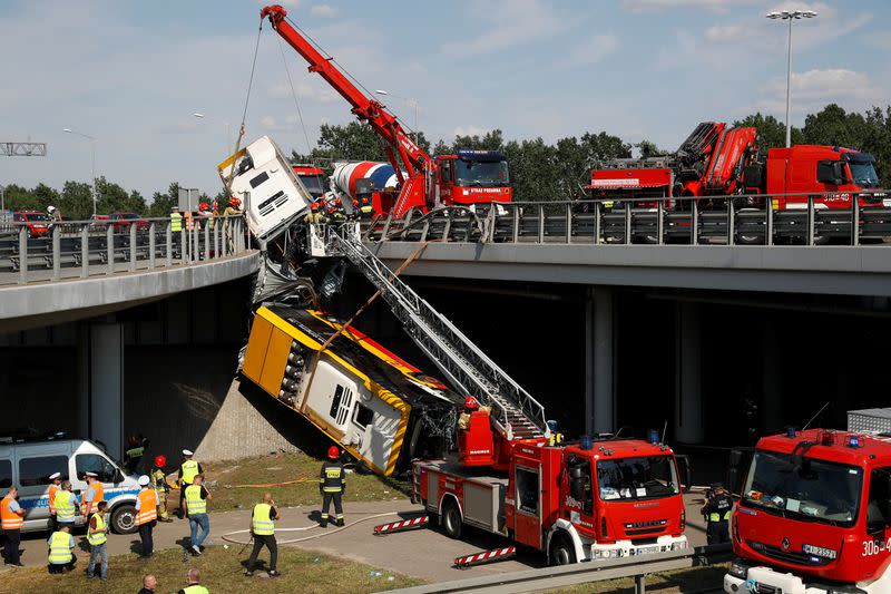 Emergency personnel work at the site of a crash after a city bus fell off a motorway bridge in Warsaw