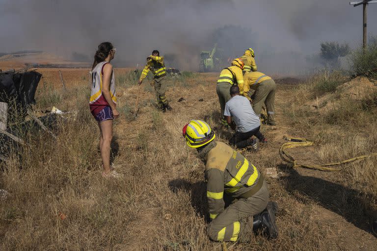 Personas trabajan para extinguir un incendio que se acerca a una casa en Tábara, noroeste de España