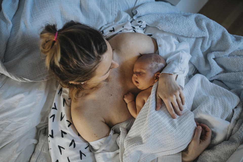 Baby sleeping on mother's chest in bed