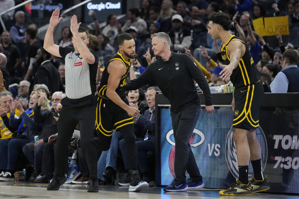 Golden State Warriors guard Stephen Curry, middle left, is congratulated by coach Steve Kerr, middle right, and forward Trayce Jackson-Davis, right, after making a 3-point basket against the Milwaukee Bucks during the first half of an NBA basketball game in San Francisco, Wednesday, March 6, 2024. (AP Photo/Jeff Chiu)