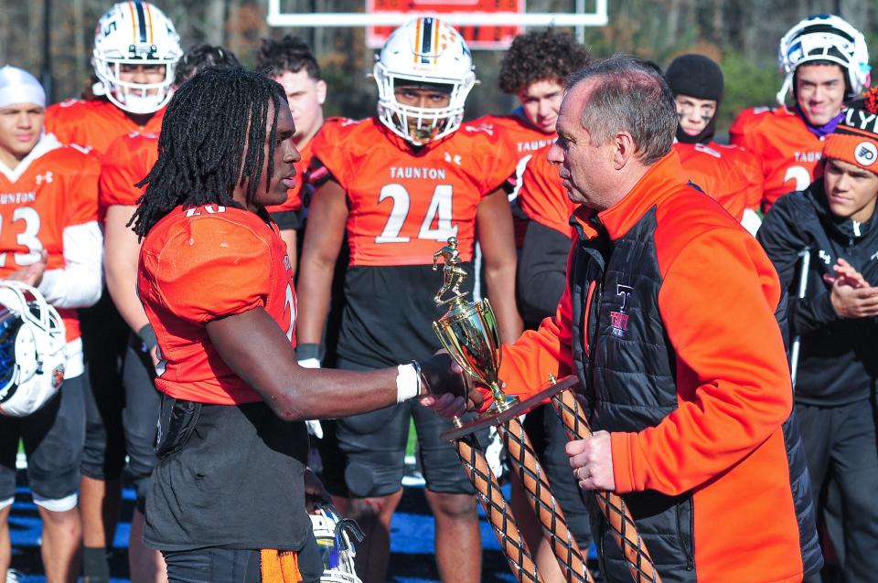 Taunton’s athletic director Mark Ottavianelli presents Malachi Johnson with the offensive player of the game award after Thursday’s Thanksgiving Day game Milford.