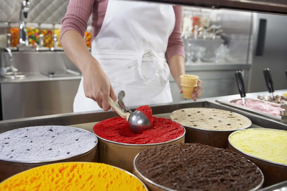 a person scooping out ice cream into a cone