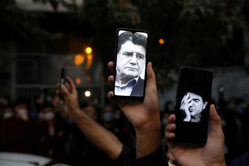 Photos of Mohammad Reza Shajarian are seen on fans' smart phones as they mourn his death in front of Jam Hospital, in Tehran