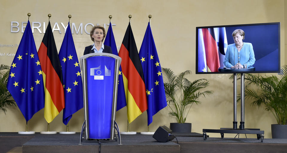 President of the European Commission Ursula von der Leyen, left rear, addresses a joint press conference with German Chancellor Angela Merkel, attending by video conference on screen right, at the start of the six month German Presidency of the EU at EU Headquarters in Brussels, Thursday, July 2, 2020. (John Thys, Pool Photo via AP)