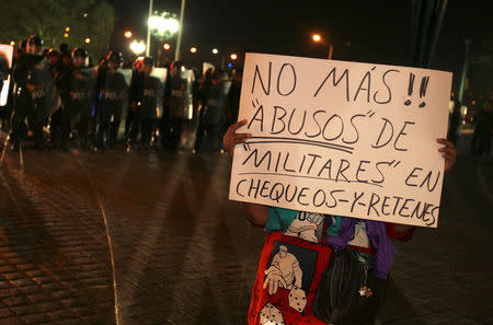 FILE PHOTO: A woman holds a sign reading "No more military abuse at the checkpoints" during a protest against the Mexican army in downtown Monterrey, northern Mexico February 10, 2009. REUTERS/Tomas Bravo/File Photo