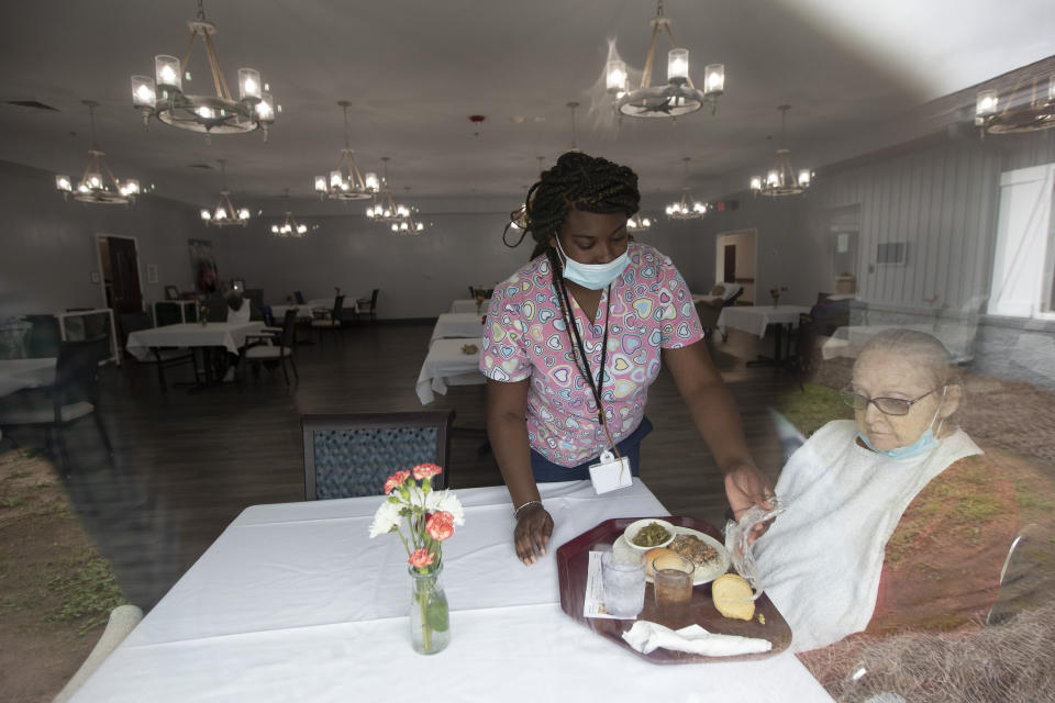 A staff member at Southern Pines nursing home helps a resident with her lunch Thursday, June 25, 2020, in Warner Robins, Ga. Residents are spaced out in the dining room and also have the choice to eat in their rooms. (AP Photo/John Bazemore)