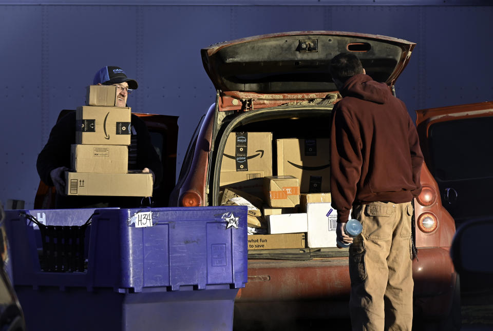 A postal worker loads Amazon packages into his car for delivery to rural areas.