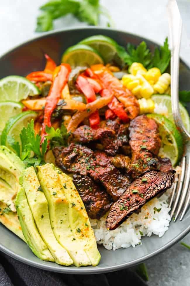 A rice bowl with steak, avocado, and bell pepper.