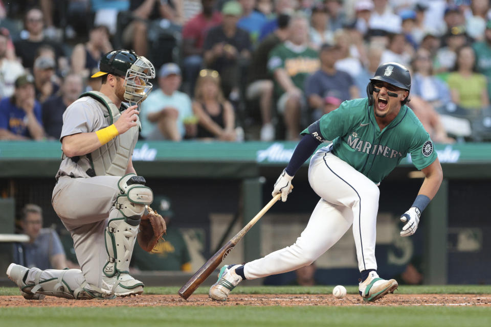 Seattle Mariners' Josh Rojas reacts after fouling a ball off, next to Oakland Athletics catcher Kyle McCann during the sixth inning of a baseball game Saturday, May 11, 2024, in Seattle. (AP Photo/Jason Redmond)