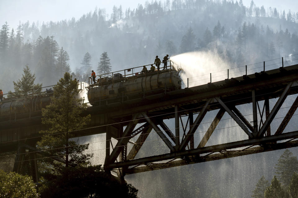 Firefighters spray water from Union Pacific Railroad's fire train while battling the Dixie Fire in Plumas National Forest, Calif., on Friday, July 16, 2021. (AP Photo/Noah Berger)