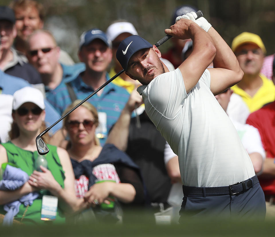 The patrons look on as Brooks Koepka hits his tee shot to the fourth green during a practice round for the Masters golf tournament Tuesday, April 9, 2019, in Augusta, Ga. (Curtis Compton/Atlanta Journal-Constitution via AP)