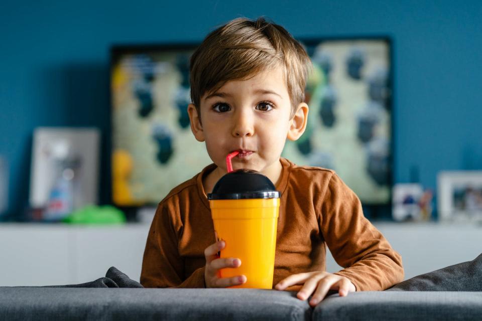 A boy drinks from a drink bottle with a straw.