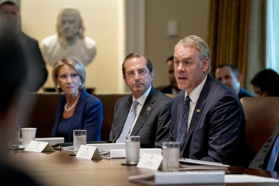 FILE - In this Thursday, Aug. 16, 2018 file photo, Interior Secretary Ryan Zinke, right, accompanied by Education Secretary Betsy DeVos, left, and Health and Human Services Secretary Alex Azar, center, speaks during a cabinet meeting in the Cabinet Room of the White House, in Washington. As former U.S. Interior Secretary Zinke exits Washington amid a cloud of unresolved ethics investigations, he says he has lived up to the conservation ideals of Teddy Roosevelt and insists the myriad allegations against him will be proven untrue. (AP Photo/Andrew Harnik, File)