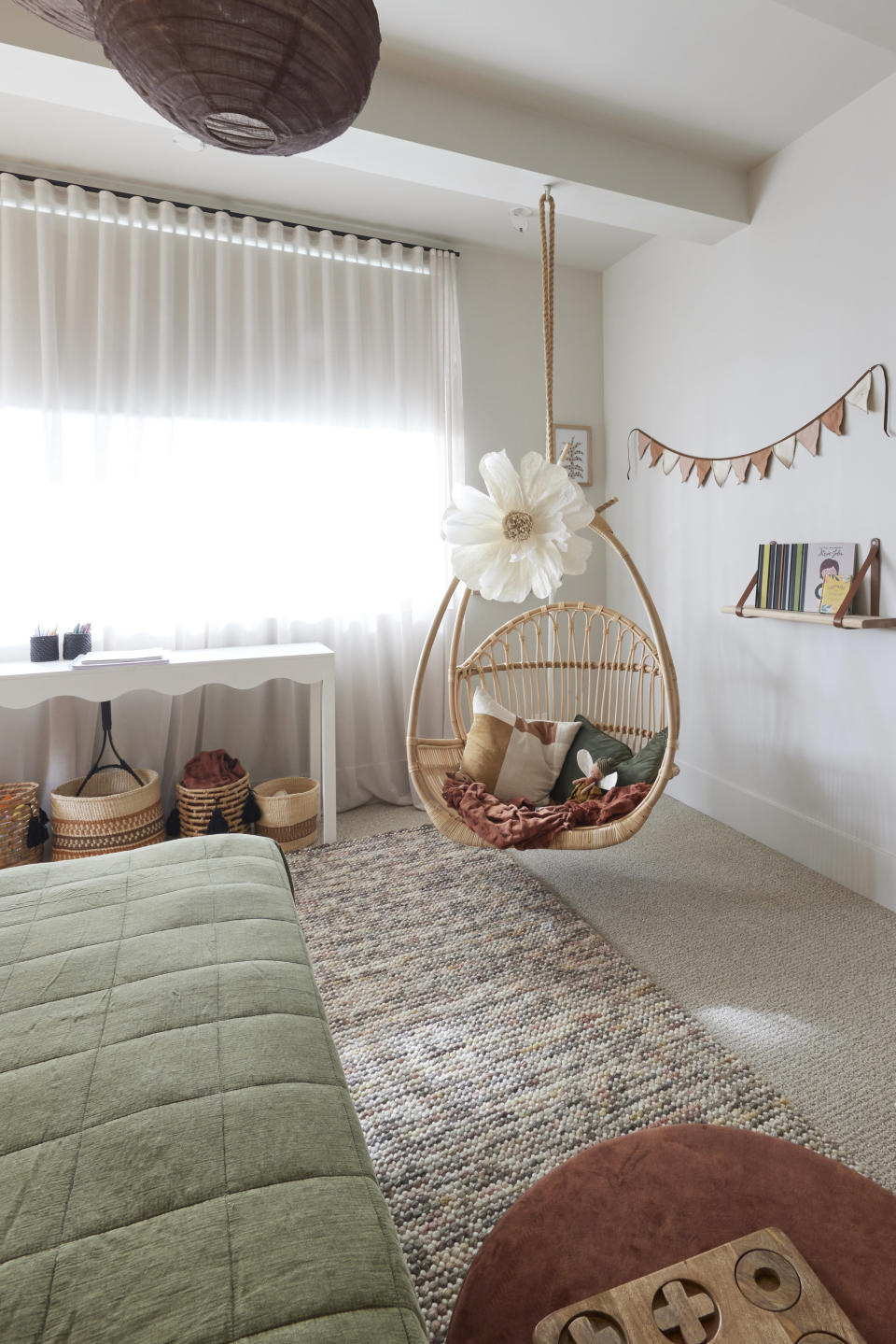 A shot of the hanging bamboo seat swing with a flower on it, and a bookshelf behind it. 