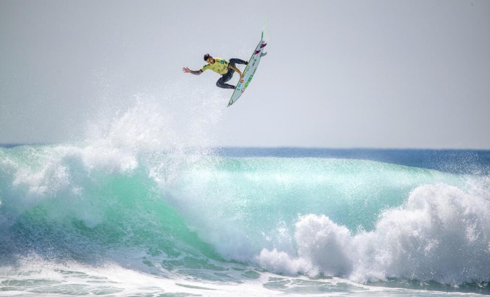 A surfer in midair above a wave