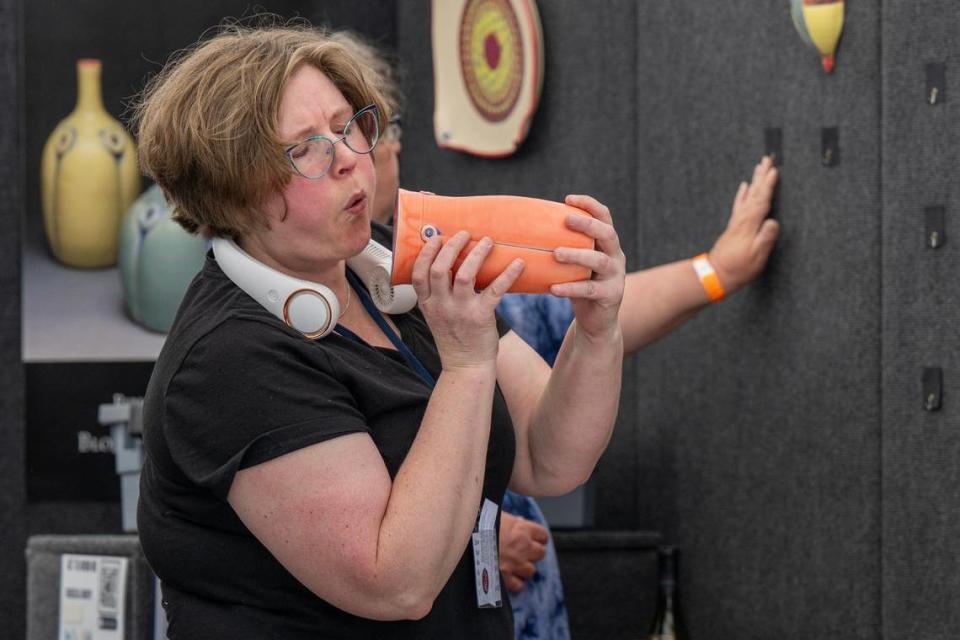 Rebecca Lowery, from Bloomington, Indiana, blows dust off her ceramics while preparing for the Brookside Art Annual.