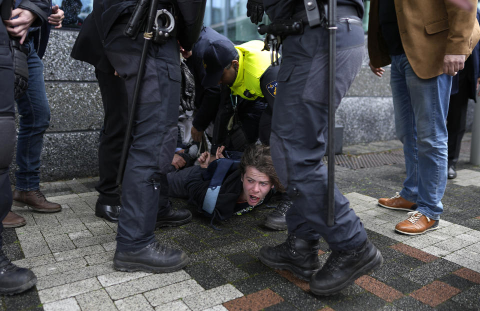 A demonstrator is detained by police officers as French President Emmanuel Macron and Dutch King Willem-Alexander arrive at the science faculty of the UvA, University of Amsterdam, Netherlands, Wednesday, April 12, 2023. Macron's two-day trip to Amsterdam and The Hague is the first state visit by a French leader since Jacques Chirac 23 years ago and underscores the close links between the Netherlands and France and the two leaders. (AP Photo/Peter Dejong)