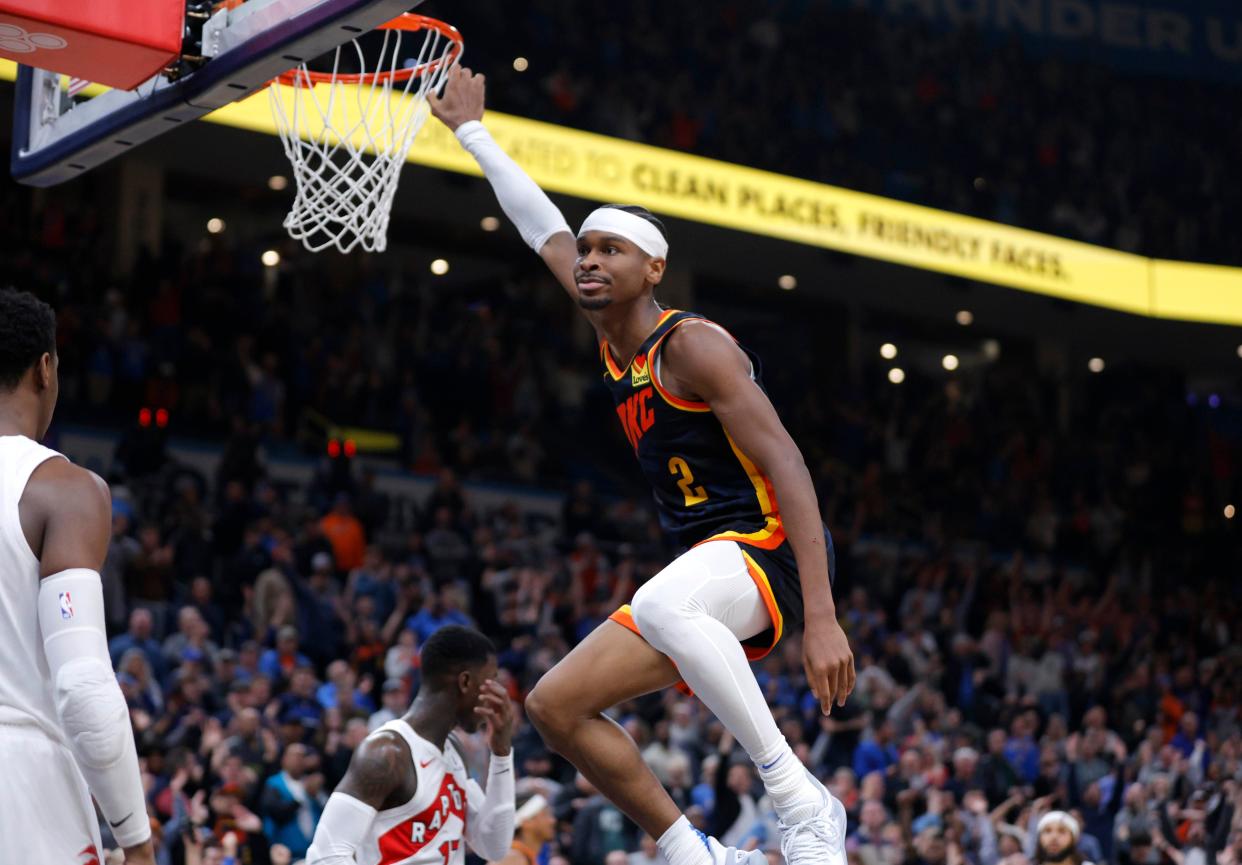 Thunder guard Shai Gilgeous-Alexander (2) hangs on the rim after a dunk in the second overtime of a 135-127 win against the Raptors on Feb. 4 at Paycom Center.