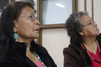 In this Jan. 14, 2020, photo, Margaret Bitsue, left, and her sister Rita Bilagody, right, listen to presentations at a forum on missing indigenous men in Tuba City, Ariz. Bitsue's days are filled with prayer: that her son has a clear mind and that he remembers home, a traditional Navajo hogan at the end of a dirt road where a faded yellow ribbon hanging from a cedar tree points to her agony. Bitsue hasn't seen or heard from Brandon Sandoval, the youngest of her four children, in more than two years. (AP Photo/Felicia Fonseca)