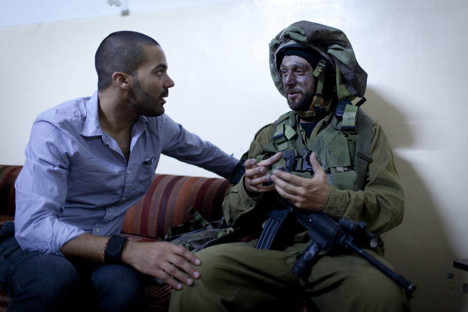 In this photo taken April 17, 2014 and released by The Warren Film, American director James Adolphus, left, directs an actor dressed in an Israeli army uniform at the filming location of his documentary, in the West Bank city of Nablus. The American director's short film about an Israeli army raid in a Palestinian refugee camp ends with a surprise _ literally involving a rabbit, though not one pulled from a hat. The story told in “The Warren” is meant to question preconceptions Israelis and Palestinians hold about each other in their long-running conflict.(AP Photo/The Warren Film)