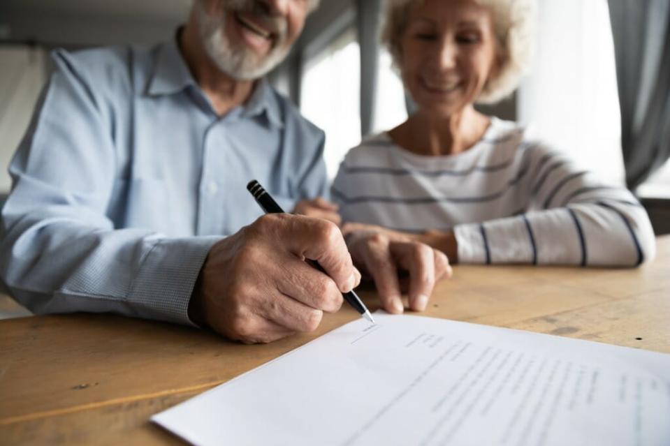 Una pareja de jubilados firma documentos hipotecarios después de obtener un préstamo hipotecario. Es posible obtener una hipoteca solo con los beneficios del Seguro Social, pero no tener ingresos regulares de un trabajo o cuentas de jubilación puede hacer que sea más difícil.