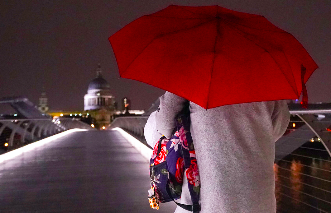 A woman walks across the Millennium bridge in London on Wednesday evening as rain started to lash the capital. (PA)