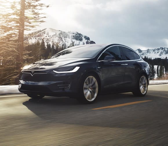 A black Tesla Model X driving on a mountain road.