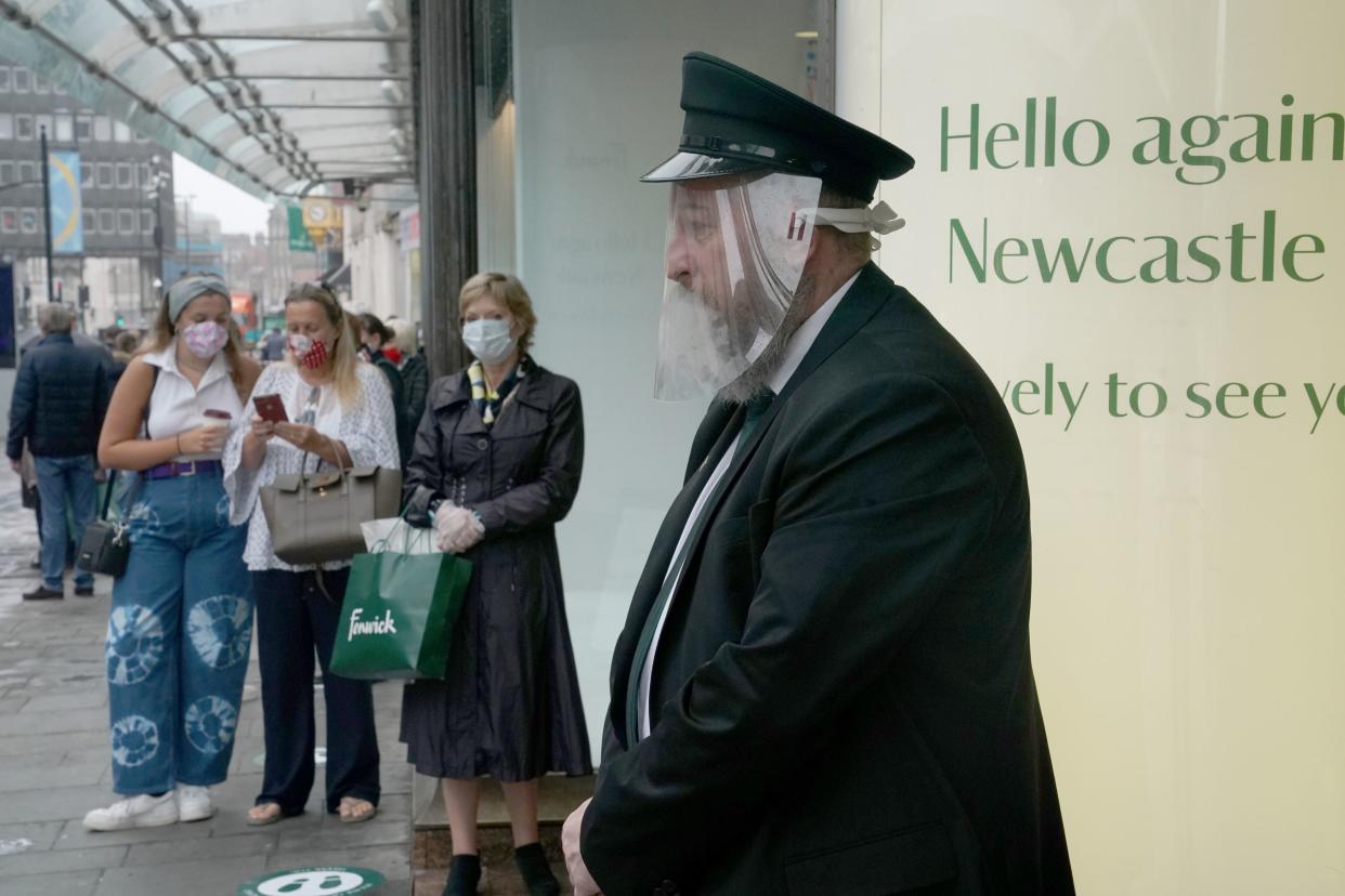 A doorman in a face mask waits to welcome back customers to the Fenwick store in Northumberland Street, Newcastle (PA)