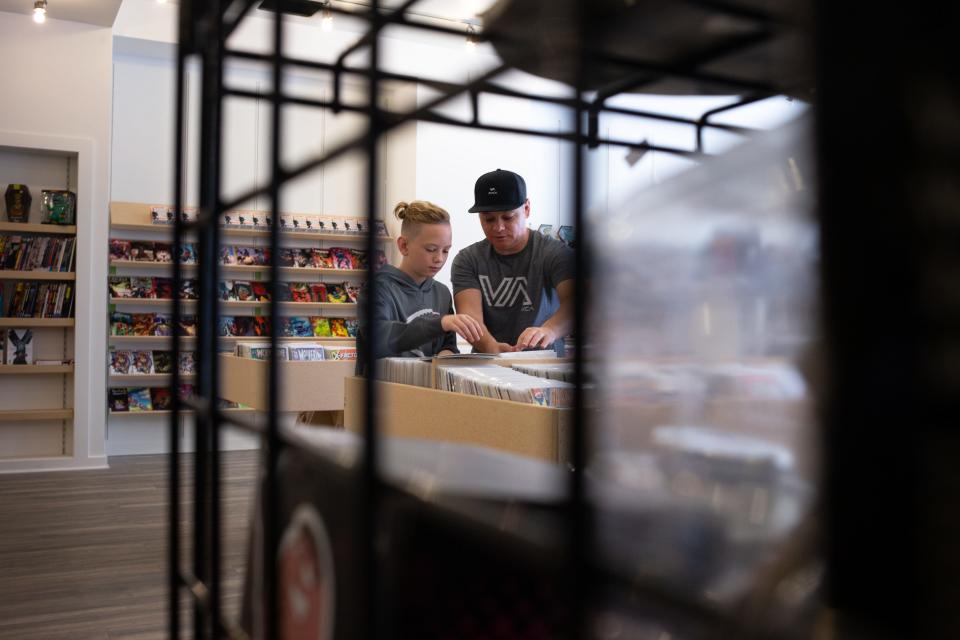 Nick Smith (right) and his son, Kristian Smith (11), look at a comic book, Nov. 24, 2021, at Atomic Comics in Gilbert, Arizona.