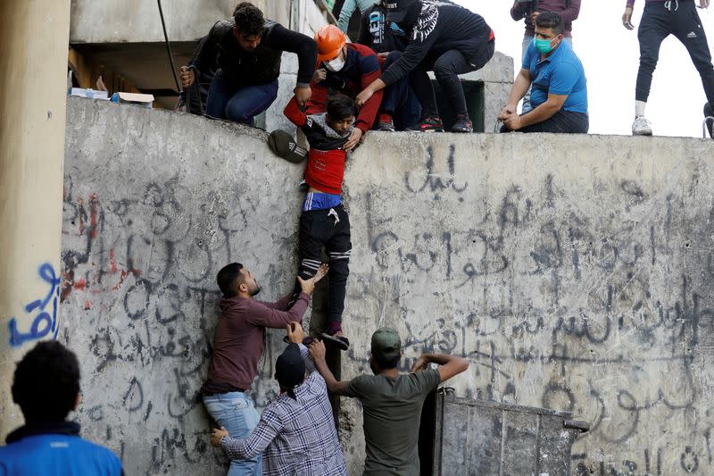 Demonstrators help a wounded young man after being hit by a stone during the ongoing anti-government protests in Baghdad