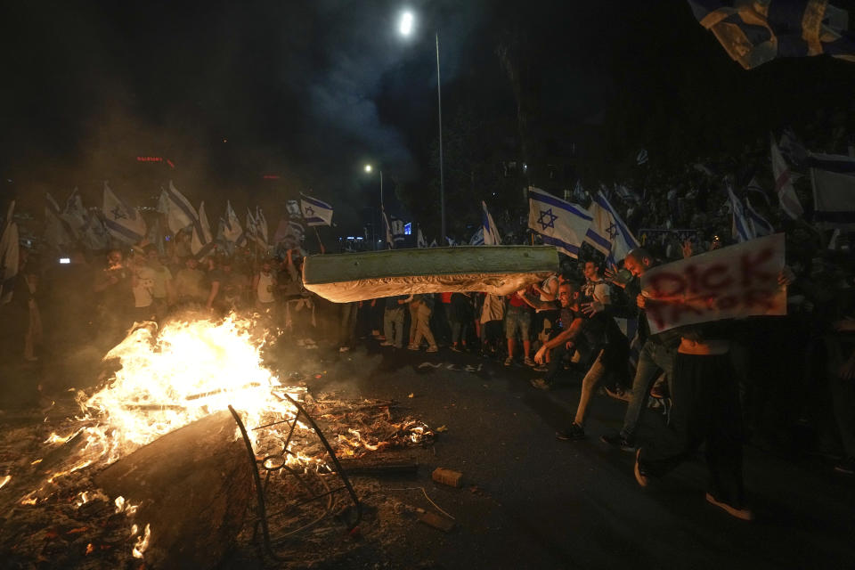 Israelis opposed to Prime Minister Benjamin Netanyahu's judicial overhaul plan set up bonfires and block a highway during a protest moments after the Israeli leader fired his defense minister, in Tel Aviv, Israel, Sunday, March 26, 2023. Defense Minister Yoav Gallant had called on Netanyahu to freeze the plan, citing deep divisions in the country and turmoil in the military. (AP Photo/Ohad Zwigenberg)