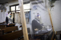 Ultra-Orthodox Jews wearing face masks during a morning prayer in a synagogue separated by plastic partitions, follow new government measures to help stop the spread of the coronavirus, in Bnei Brak, Israel, Friday, Sept 18, 2020. Israel is set to go back into a three-week lockdown later Friday to try to contain a coronavirus outbreak that has steadily worsened for months as its government has been plagued by indecision and infighting. The closures coincide with the Jewish High Holidays, when people typically visit their families and gather for large prayer services. (AP Photo/Oded Balilty)