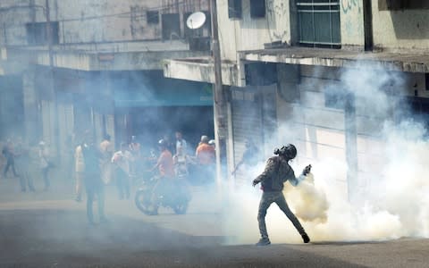 A demonstrator throws back a gas canister while clashing with security forces during a rally against Venezuelan President Nicolas Maduro - Credit: &nbsp;CARLOS EDUARDO RAMIREZ/&nbsp;REUTERS