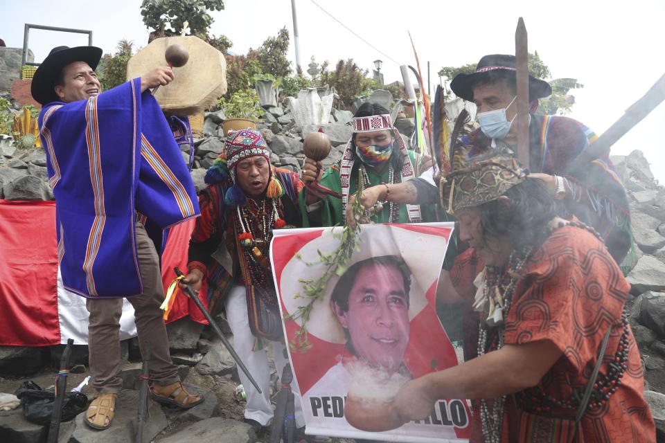 Shamans hold a photo of presidential candidate Pedro Castillo of the Free Peru party, as they perform a good luck ritual ahead of the presidential runoff election, at the Cerro San Cristobal in Lima, Peru, Wednesday, May 26, 2021. The June 6 runoff pits Castillo against Keiko Fujimori, the daughter of former President Alberto Fujimori. (AP Photo/Martin Mejia)