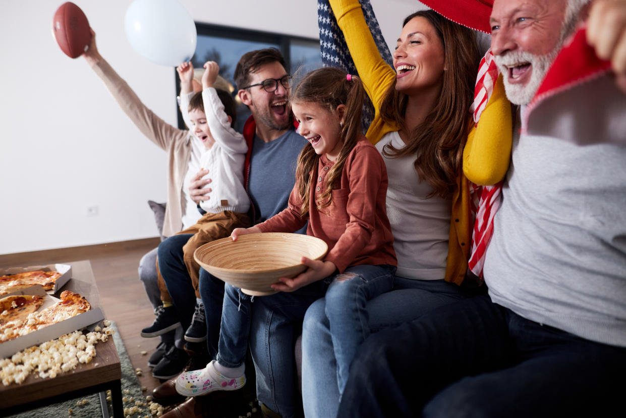  Cheerful extended family watching sports game on TV at home. 