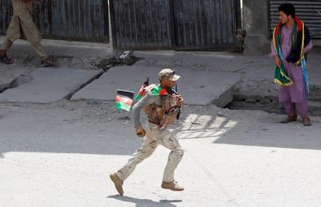 A member of Afghan security forces runs after a blast in Jalalabad