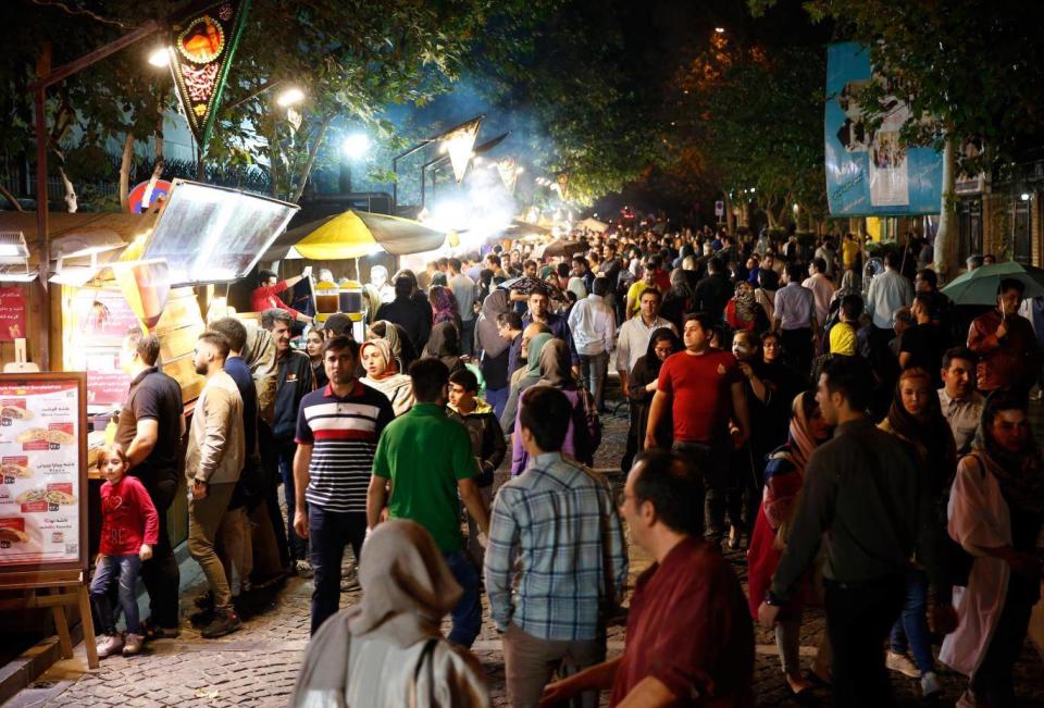 Iranians queue at a street food market in Tehran last month (EPA)