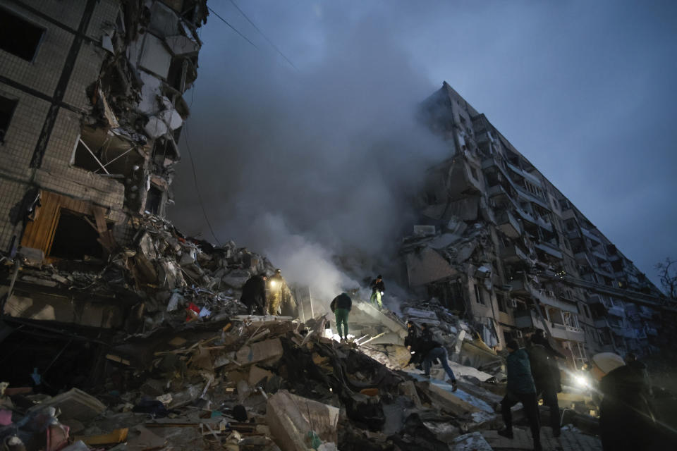 Local residents clear the rubble after a Russian rocket hit a multistory building leaving many people under debris in Dnipro, Ukraine, Saturday, Jan. 14, 2023. (AP Photo/Roman Chop)