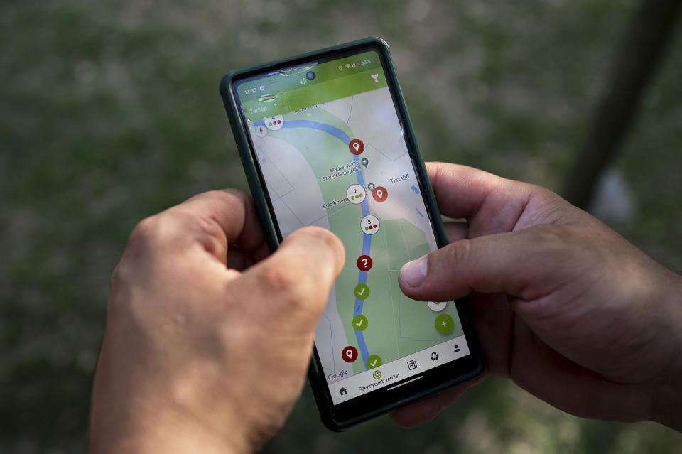 A volunteer uses his phone to look at the reported rubbish dumps on the banks of the Tisza River while attending the Plastic Cup event near Tiszaroff, Hungary, Wednesday, Aug. 2, 2023. The annual competition has gathered around 330 tons of waste from the Tisza since 2013. Their aim is to preserve Hungary's natural environment, but also to head off a mounting global plastic waste crisis by cutting it off early in the cycle. (AP Photo/Denes Erdos)