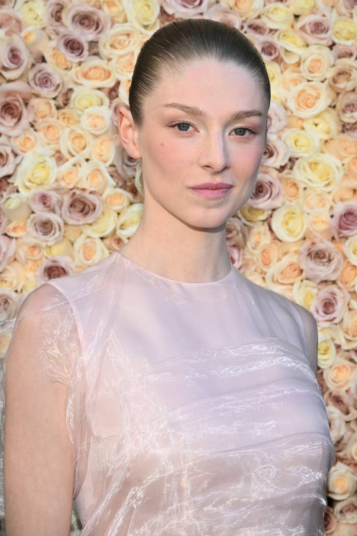 Woman in a sheer outfit posing in front of a floral backdrop