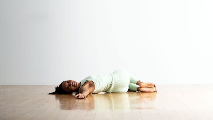 A woman demonstrates Reclined Supine Spinal Twist in yoga