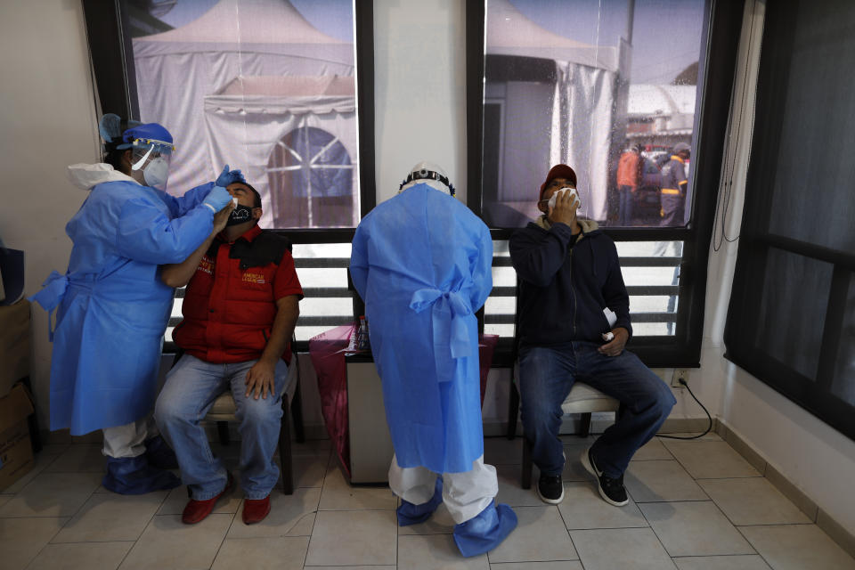 Medical staff collect nasal swabs for rapid and PCR tests inside a COVID-19 health post that has been set up in the Central de Abastos, the capital's main market, in Mexico City, Tuesday, Dec. 8, 2020.(AP Photo/Rebecca Blackwell)