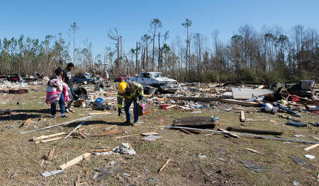 Residents of Sunshine Acres mobile home park with the assistance of firefighters search for items after being allowed into their homes after a tornado struck the mobile home park in Adel, Georgia, U.S., January 24, 2017. REUTERS/Tami Chappell