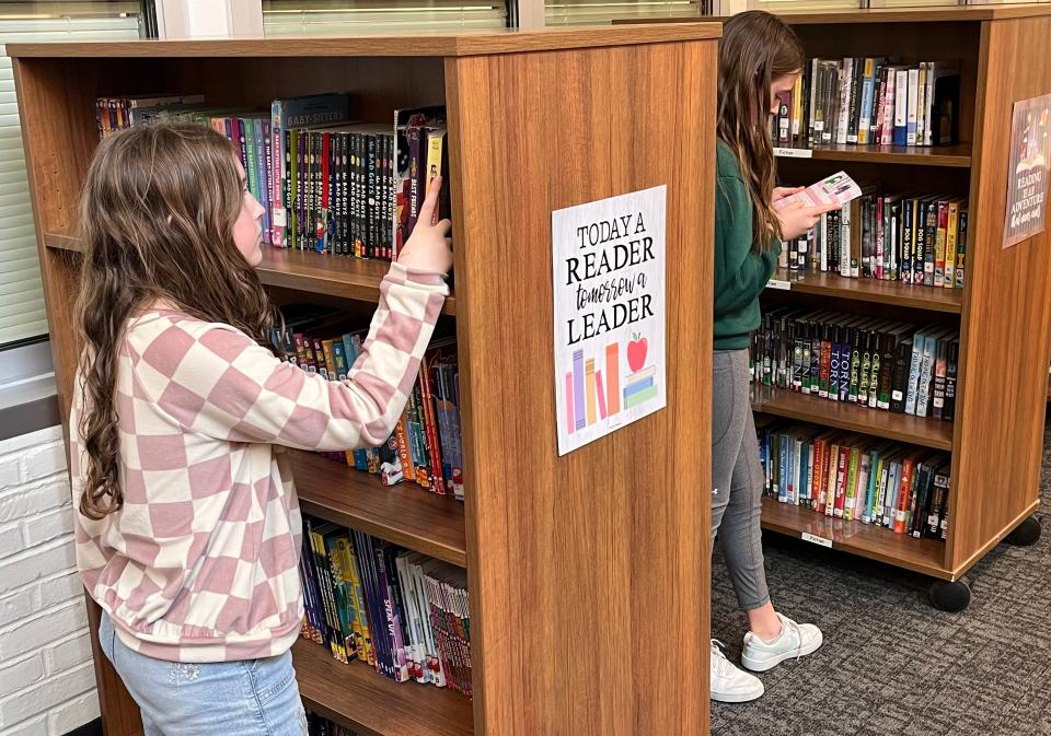 Johnstown Intermediate School fifth-graders Camille Bartley and Brooklyn Metzger each look for a book during a 30-minute period Wednesday with librarian Brandie Peterman.